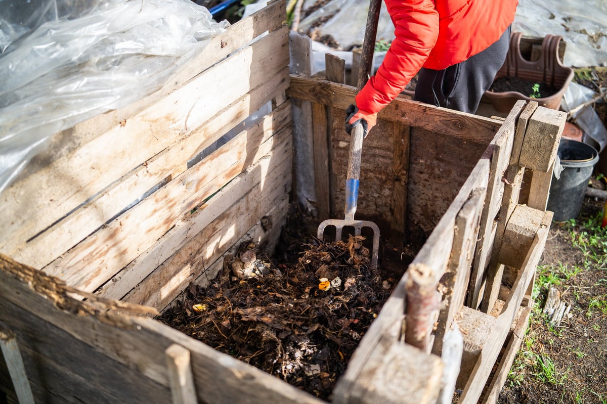Persona removiendo compost orgánico con una horca de jardín